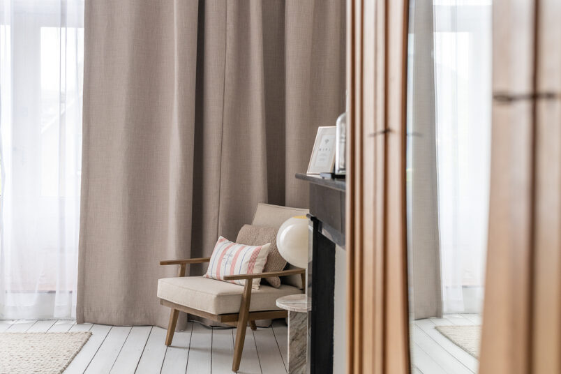 linen curtains in neutral bedroom with armchair